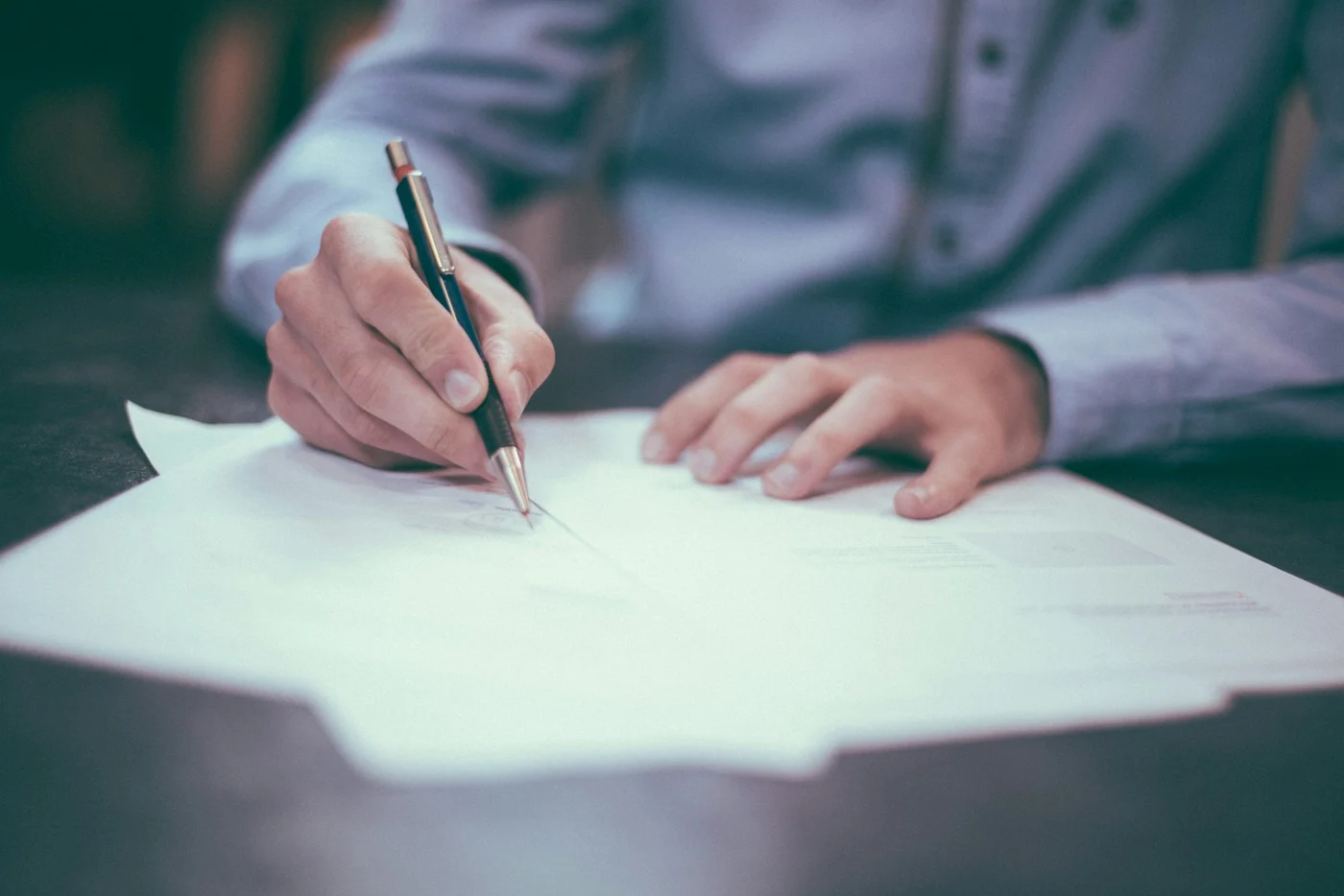 Person reviewing and signing consent documents at a desk in a calm, professional setting